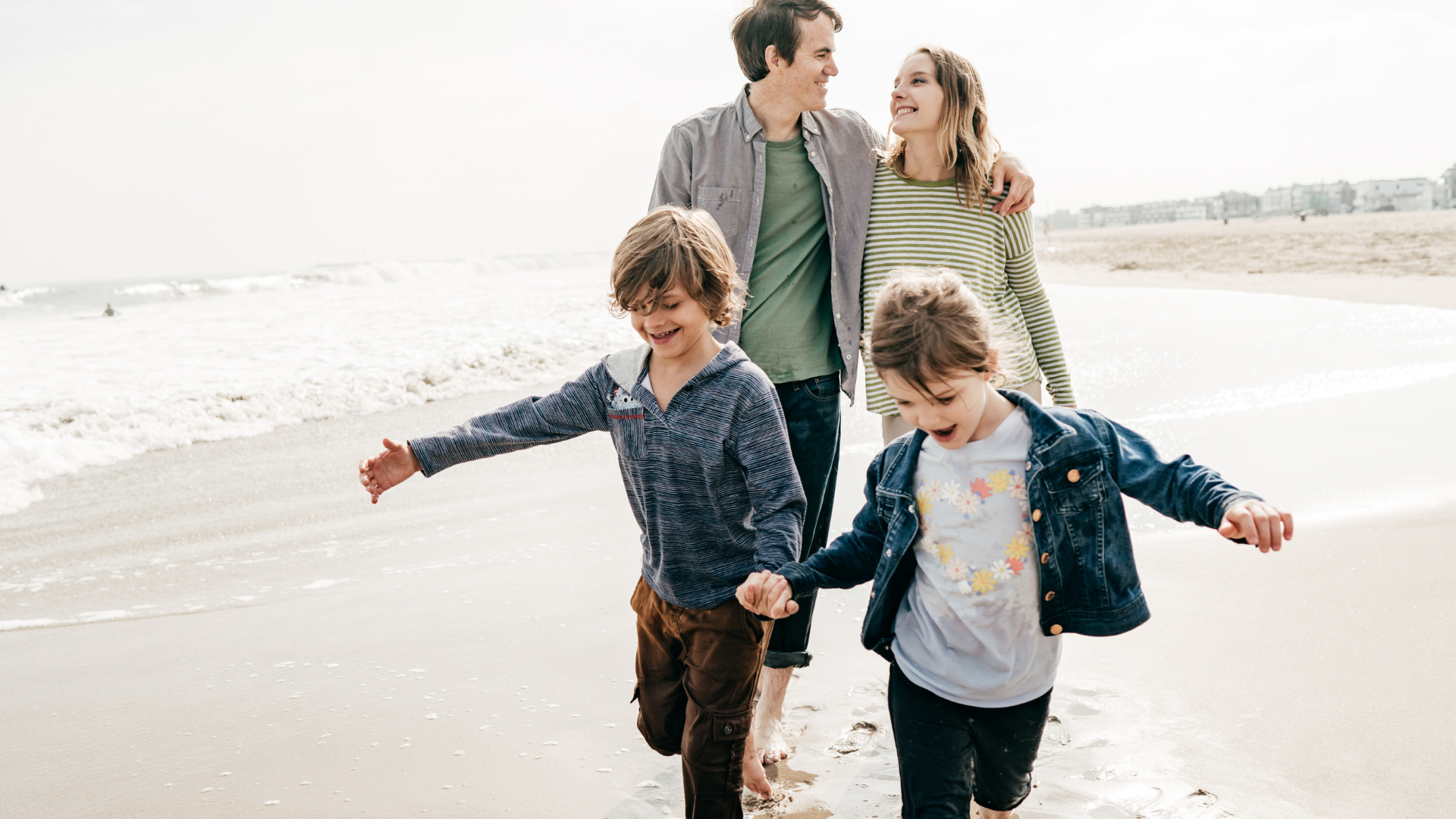 A young family walking along the beach together at golden hour.